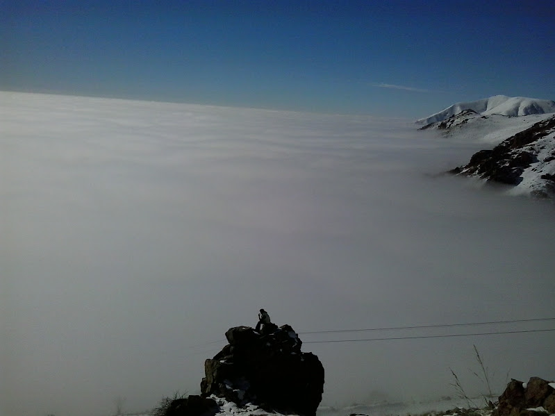 Person sitting on a rock above the clouds